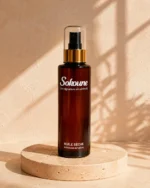 Huile sèche corps et cheveux Sokoune, flacon spray ambré 200 ml sur socle en travertin