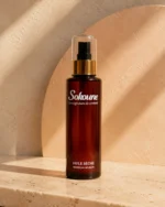 Flacon d'huile sèche Sokoune à l'huile d'argan, lumière chaude et ombres de feuillage